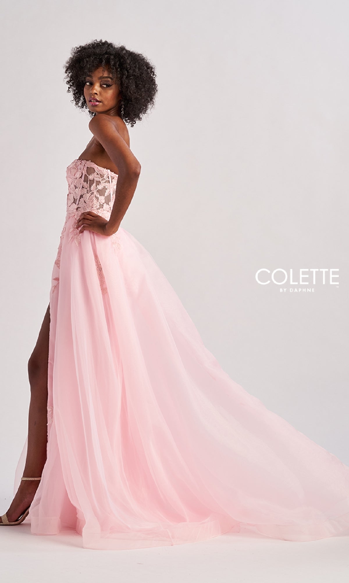 A woman models the Colette CL8660 long prom dress, featuring a strapless design with a sheer lace bodice and a floor-length embroidered A-line skirt, standing against a plain background.